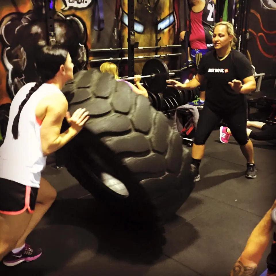 A coach guiding an Xtreme Athlete client through a tyre exercise